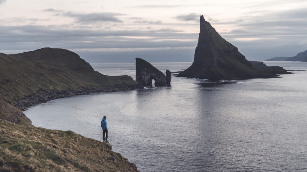 a man standing on a cliff with a beautiful view of the sea and cliffs