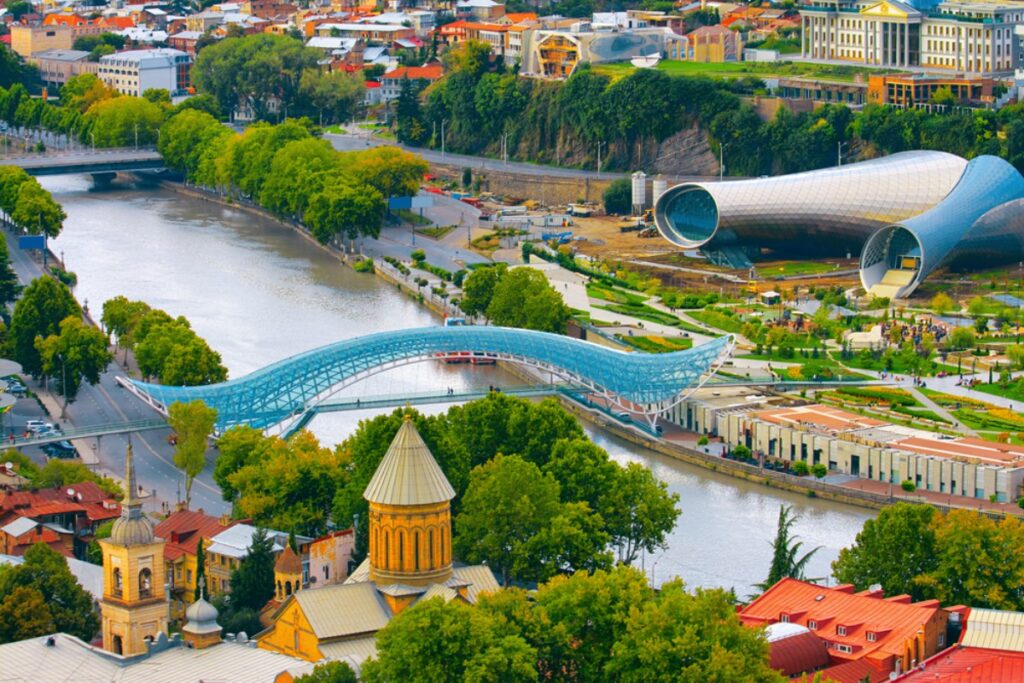 photo of the art bridge over the river in Georgia against the background of unusual buildings