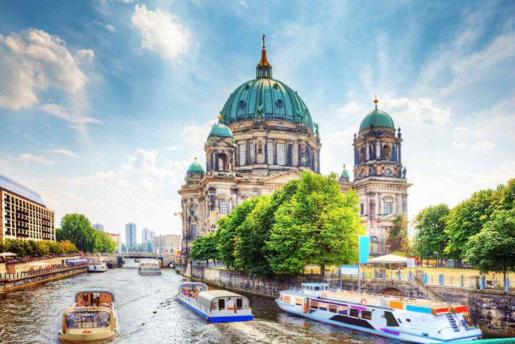 beautiful photo of Berlin Cathedral in Germany from the side of the river where ferries and boats are sailing on a sunny day