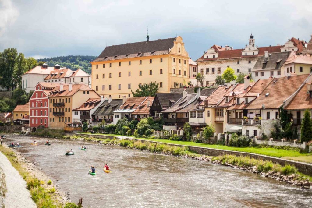 Photo of Cesky Krumlov, a UNESCO Heritage Site in the Czech Republic, with people kayaking on the river in the background