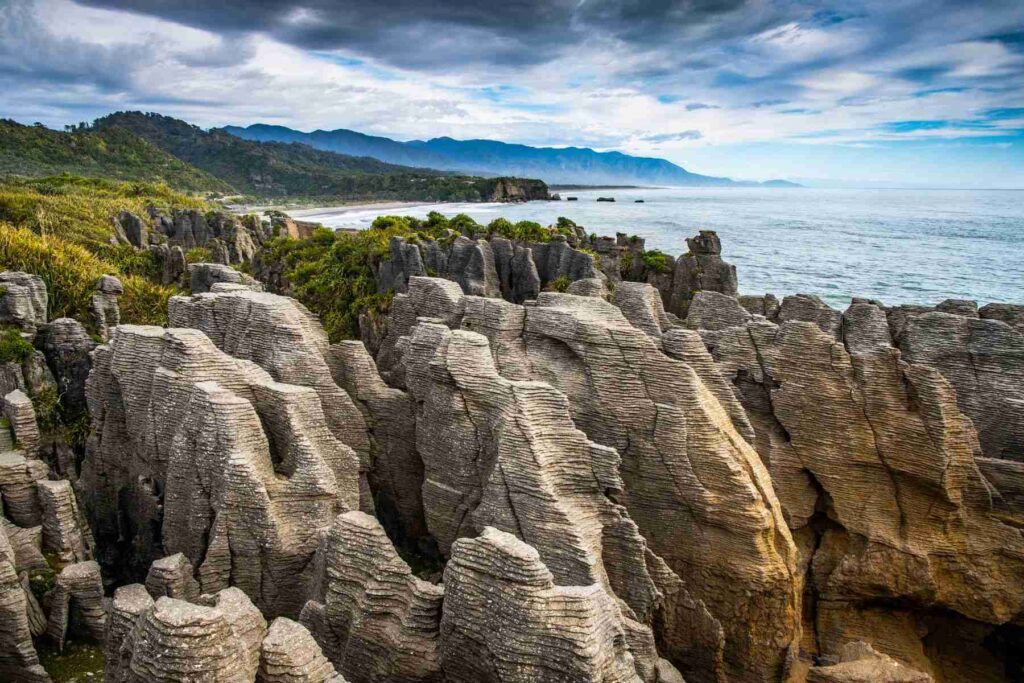 photo of an incredible place in New Zealand - Pancake Rocks in Punakaiki with the ocean and trees in the background