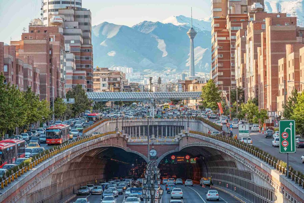 photo of dense traffic in Tohid tunnel against the background of Milad Tower, Alborz Mountains in Tehran, Iran