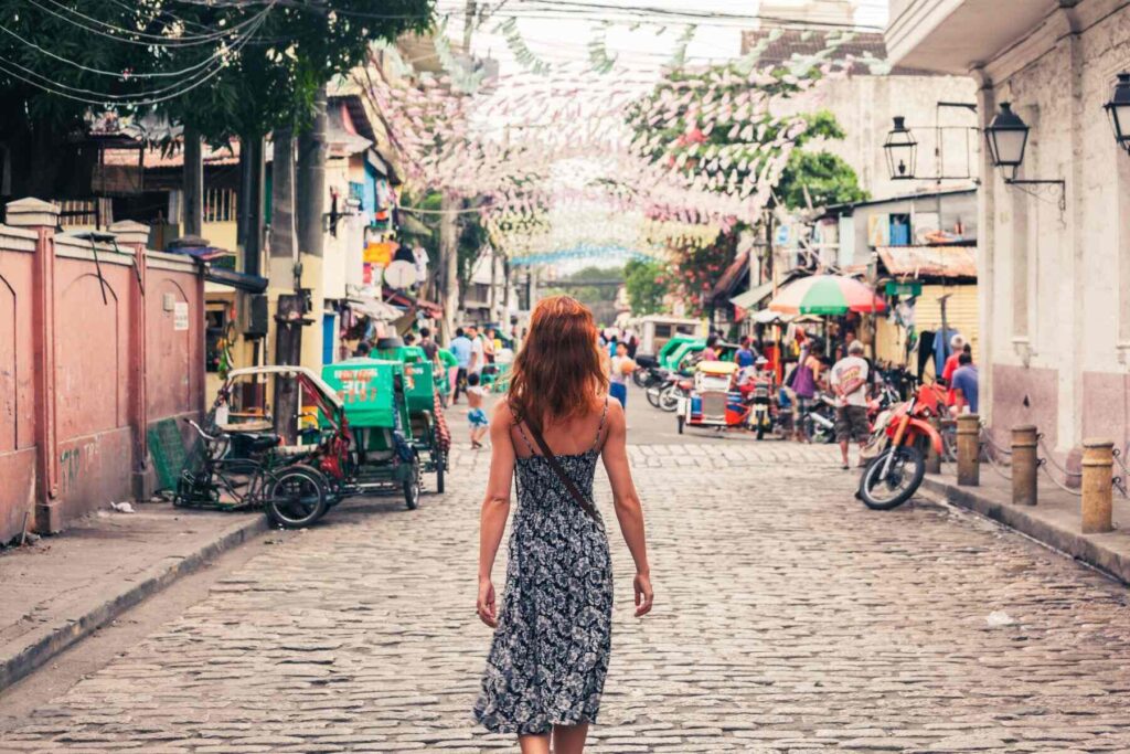 A girl in a black and white dress walks down an old street in Manila city